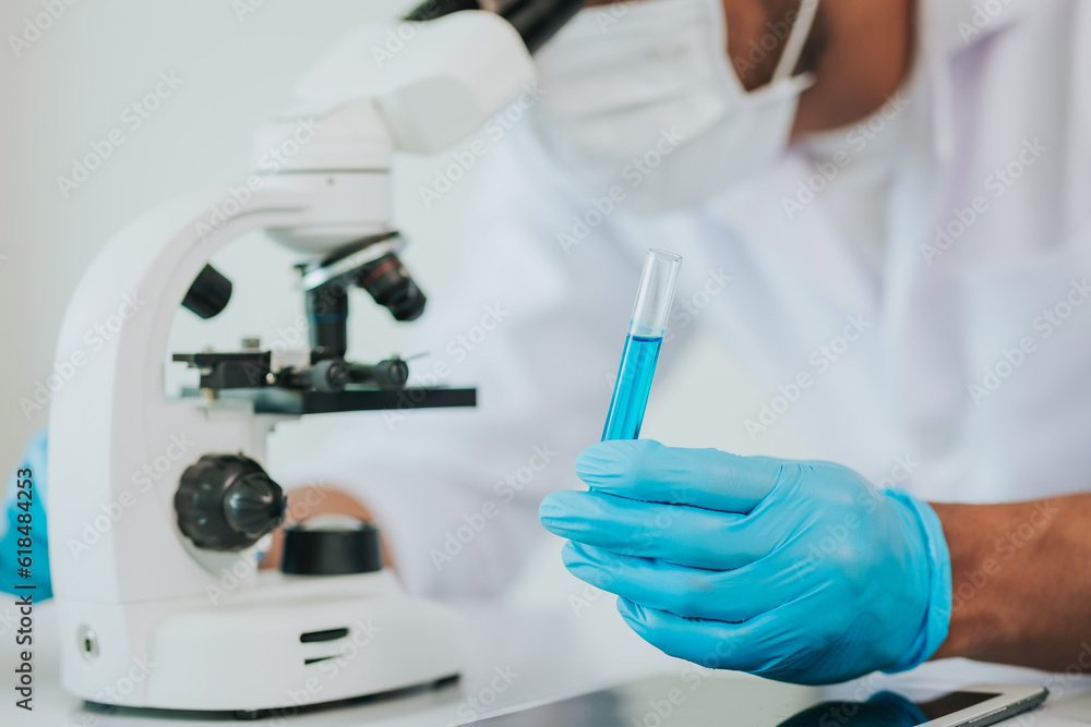 Medical science laboratory: Portrait of a scientist looking under a microscope analyzing a test sample. Works with advanced devices Medical science laboratory: Portrait of a scientist looking under a microscope analyzing a test sample. Works with advanced devices