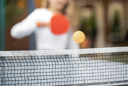 The girl plays table tennis. A girl hits a table tennis ball with a racket. Submission of the ball. Sport games. Sport lifestyle concept.