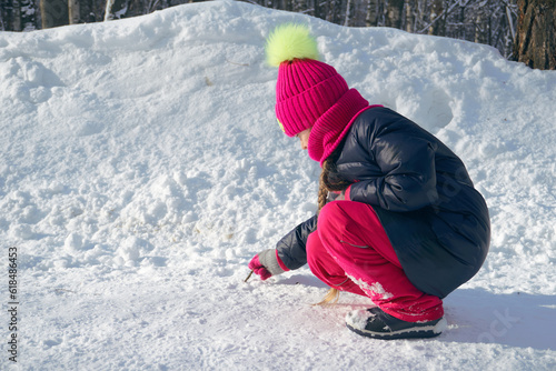 A girl child plays snowballs in winter, walks on snowdrifts. Forest park and a walk in the fresh air. Selection Focus