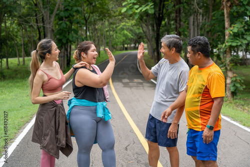 A group of 2 male and 2 female runners giving each other high five to celebrate their running success at a running track of a local park © kudosstudio