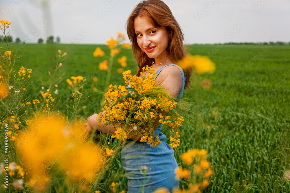 The girl holds in her hands a bouquet of rapeseed and spikelets of wheat The girl holds in her hands a bouquet of rapeseed and spikelets of wheat