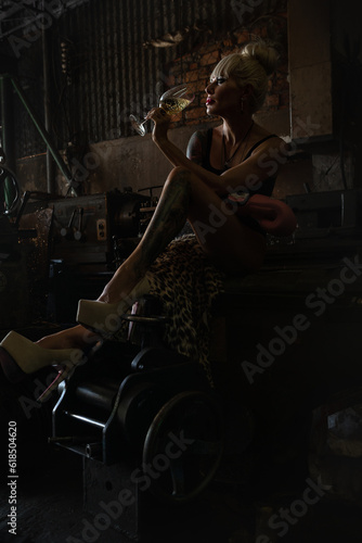 Fashion photo of beautiful sportive woman drinking champagne in a garage