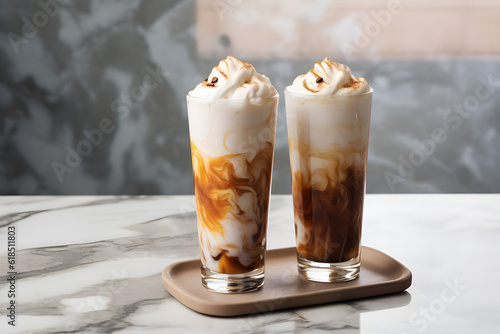 two tall glasses with warm coffee drink with cinnamon, whipped milk foam and caramel on a marble board. Generative AI technology photo