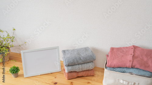 たたまれた冬物の服と白いフレーム｜洗濯物・衣替え・リサイクル イメージ