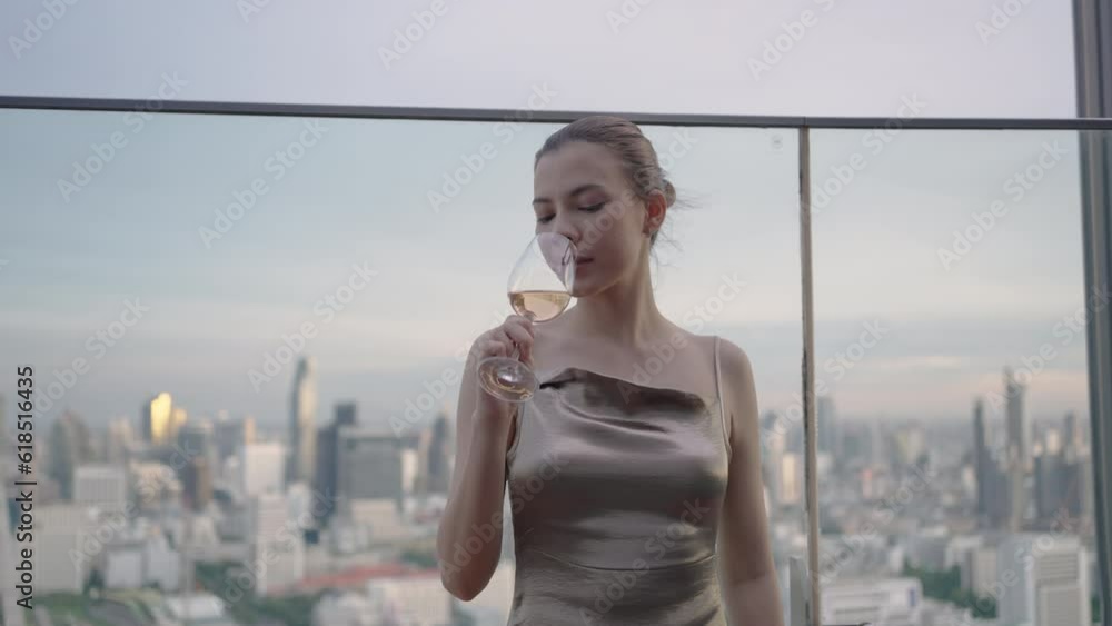 Elegant young woman in a golden dress drink pink rose wine at the rooftop bar of a luxury hotel in the city. Elegant young woman in a golden dress drink pink rose wine at the rooftop bar of a luxury hotel in the city.