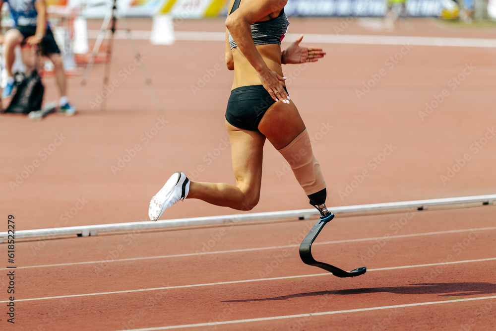 Wall mural female para athlete on prosthetic leg running track stadium