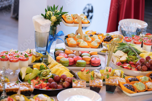 candy bar dessert table with various macarons, sweets, cupcakes, fruits and pies.