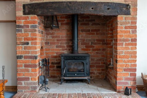 Tableau sur toile Modern cast-iron wood stove with a red brick surround in the living room
