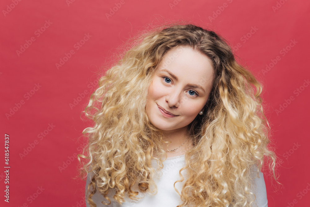 Attractive woman with curly hair, blue eyes. Positive gaze, satisfied. Pink background Attractive woman with curly hair, blue eyes. Positive gaze, satisfied. Pink background