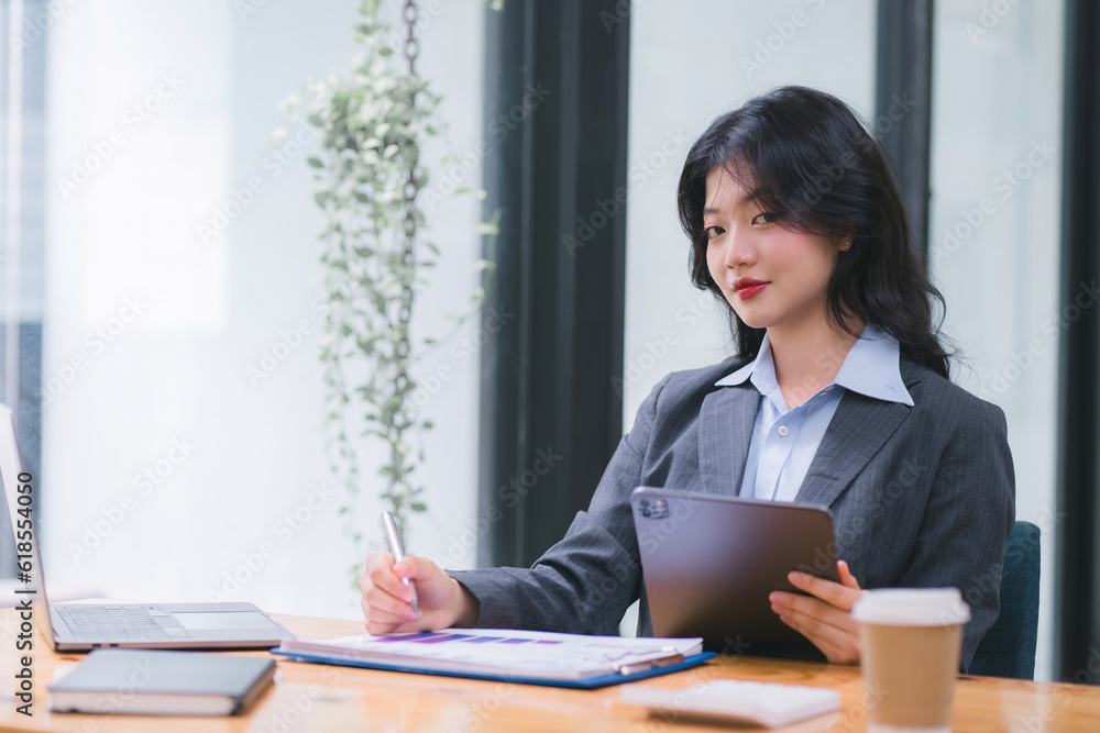 Smiling young Asian businesswoman leader holding a digital tablet, working in an office. Professional executive manager or saleswoman using corporate technology, confidently. Smiling young Asian businesswoman leader holding a digital tablet, working in an office. Professional executive manager or saleswoman using corporate technology, confidently.