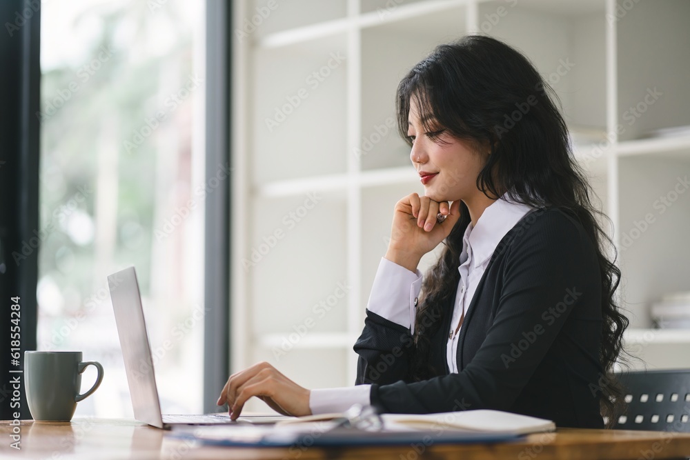 A portrait of a smiling, young, beautiful, professional, and confident millennial caucasian businesswoman using a digital tablet to analyze sales data at a modern office. A portrait of a smiling, young, beautiful, professional, and confident millennial caucasian businesswoman using a digital tablet to analyze sales data at a modern office.