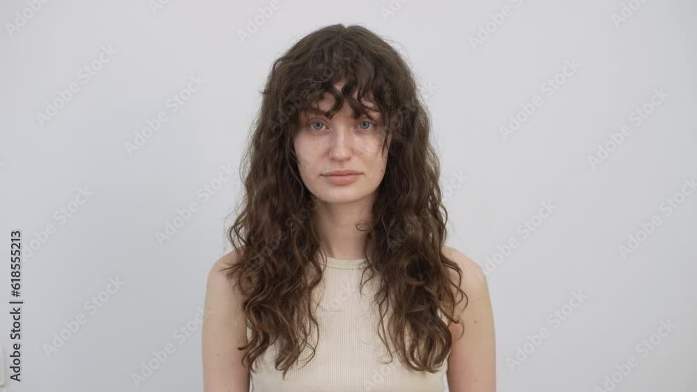 Studio portrait of pretty young woman before applying professional makeup and making stylish hairstyle standing on isolated white background, looking at camera. Concept of before and after. Studio portrait of pretty young woman before applying professional makeup and making stylish hairstyle standing on isolated white background, looking at camera. Concept of before and after.
