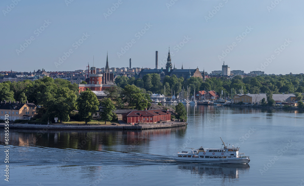 Archipelago ferry in the bay Strömmen passing the castle on the island Kastellholmen, mirror water reflecting, a sunny summer morning in Stockholm