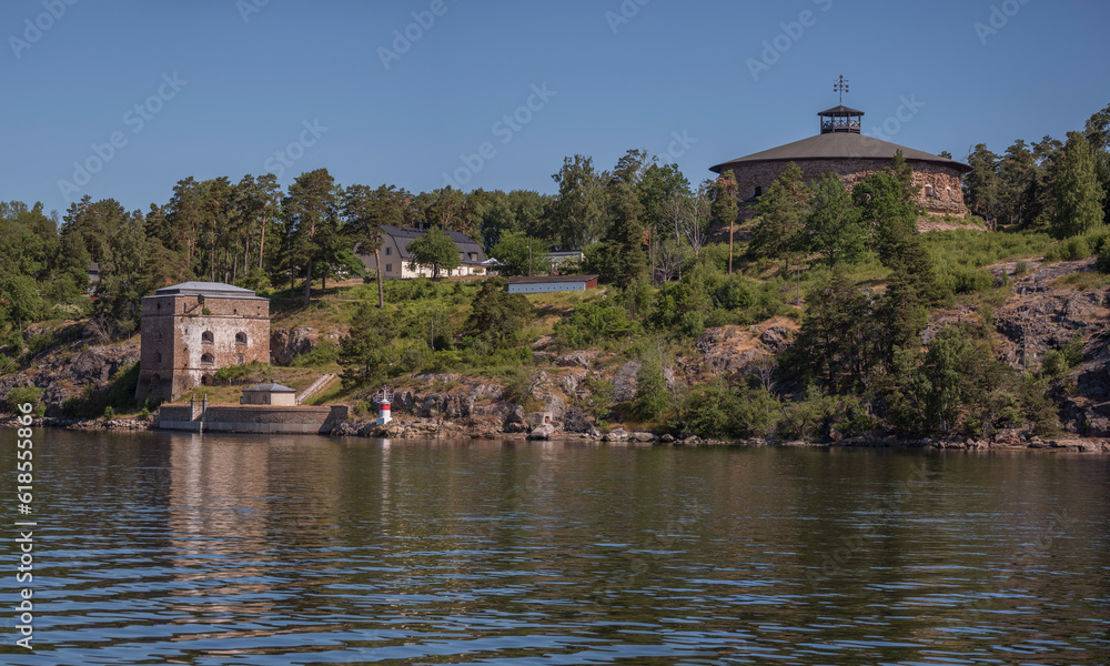 Redoubt and defense tower with optical signal on roof at the gate Oxdjupet in the archipelago, yellow road ferry, a sunny summer morning in Stockholm