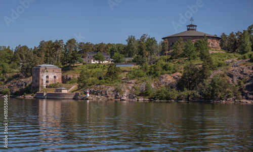 Redoubt and defense tower with optical signal on roof at the gate Oxdjupet in the archipelago, yellow road ferry, a sunny summer morning in Stockholm