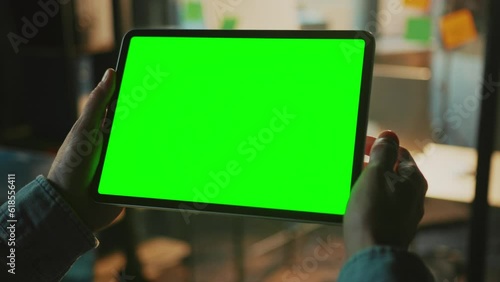 Horizontal shot of digital tablet in man's hands. Unrecognizable man touching green screen, swiping. Businessman looking pad screen. Work concept. Indoors. Blurred background