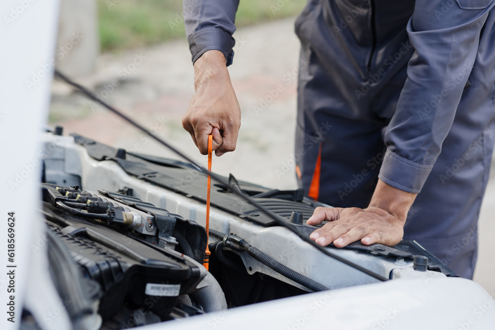 A mechanic checks the engine oil level. off-site car service. A mechanic checks the engine oil level. off-site car service.