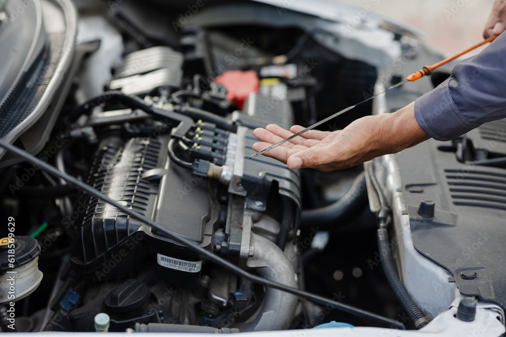 A mechanic checks the engine oil level. off-site car service. A mechanic checks the engine oil level. off-site car service.