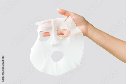 hand holding moisturising face mask isolated on gray background