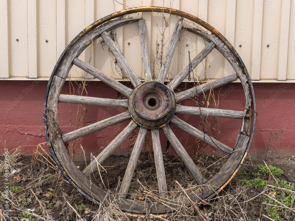 old wagon wheel leaning against a barn old wagon wheel leaning against a barn