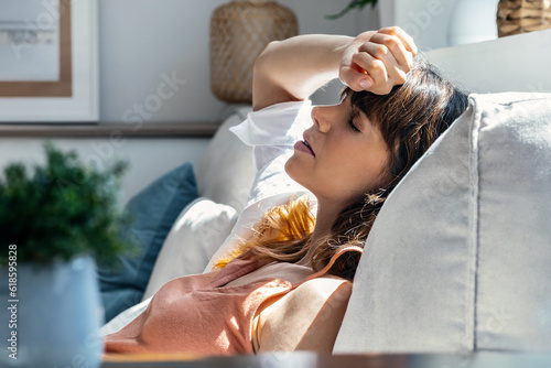 Beautiful tired woman relaxing on couch in living room at home