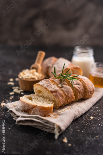 Sliced artisan baguette bread on wooden coaster and rustic background. Sourdough bread.