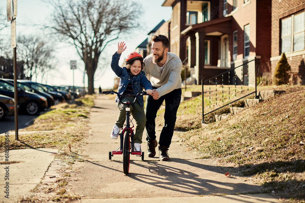 Father teaching his son how to ride a bike in the suburbs - obrazy, fototapety, plakaty 