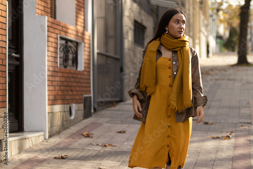 Ethnic young woman walking down the street on an autumn day. Composite colors.