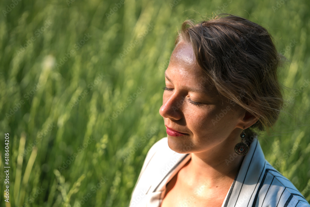 A young blonde woman meditates on the grass in the park during a lunch break. A young blonde woman meditates on the grass in the park during a lunch break.