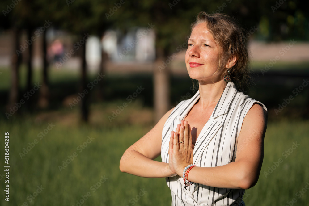 A young blonde woman meditates on the grass in the park during a lunch break. A young blonde woman meditates on the grass in the park during a lunch break.