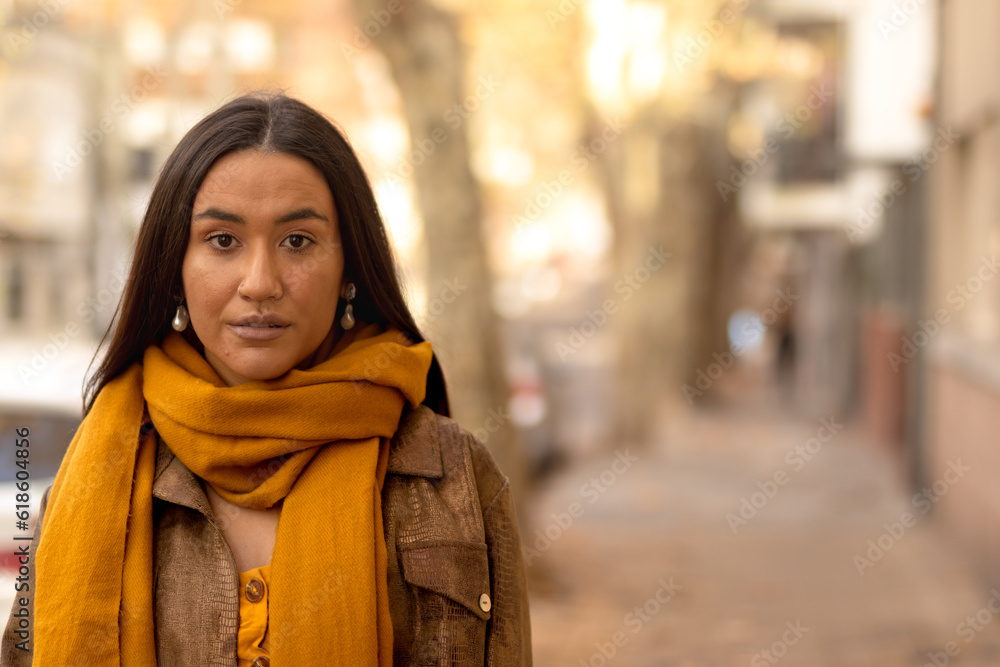 Native young woman looking at camera with autumn background in street. Copyspace. Native young woman looking at camera with autumn background in street. Copyspace.