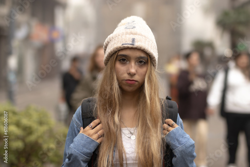 Beautiful and attractive young woman looking at camera in city pedestrian. Background of blurred people and monuments.