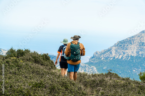 A couple of hikers, walking in nature with mountains in the background. 