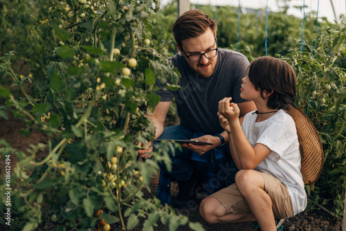 Father is teaching his son about gardening in their greenhouse.