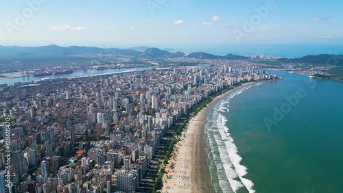 Ascending view of the coastal city in Brazil. Aerial view of the entire Baixada Santista. Beach with colorful umbrellas and beautiful waves. Port of Santos in the background. Santos, São Paulo, Brazil photo