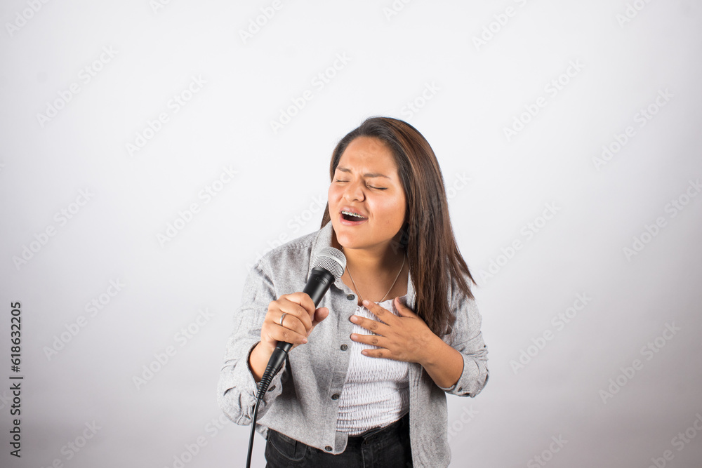 photo of latin woman singing passionately with a microphone on light studio background. Concept of people and hobbies. photo of latin woman singing passionately with a microphone on light studio background. Concept of people and hobbies.