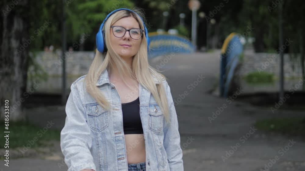 Woman in headphones. Girl with headphones in the park. Listening to music and walking in park. Woman in headphones dancing in city street Woman in headphones. Girl with headphones in the park. Listening to music and walking in park. Woman in headphones dancing in city street