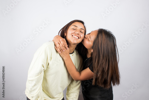 Portrait of two young women embracing on a white studio background. Concept of people.