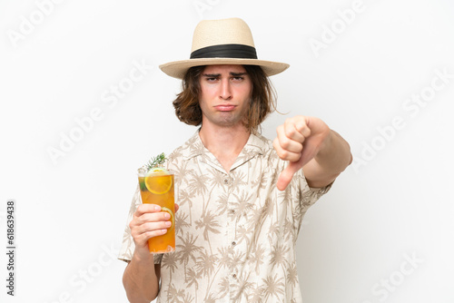 Young handsome man holding a cocktail isolated on white background showing thumb down with negative expression
