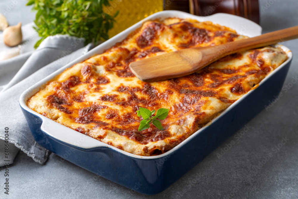 Portion of ground beef lasagna topped with melted cheese and garnished with fresh parsley served on a plate in close view for a menu