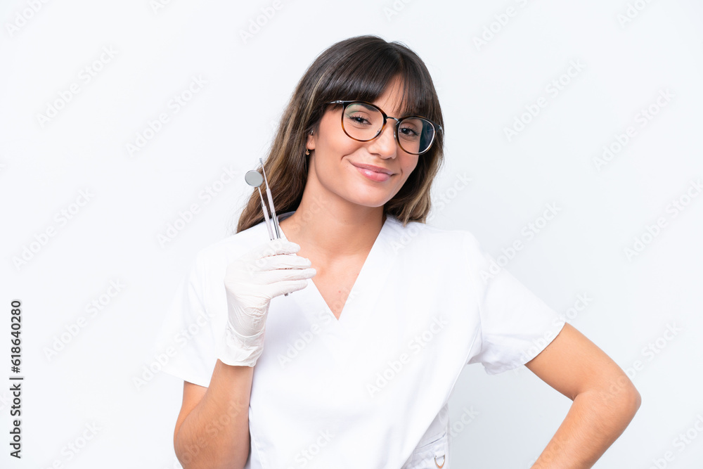 Dentist caucasian woman holding tools isolated on white background posing with arms at hip and smiling Dentist caucasian woman holding tools isolated on white background posing with arms at hip and smiling