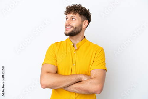 Young handsome caucasian man isolated on white background looking up while smiling © luismolinero