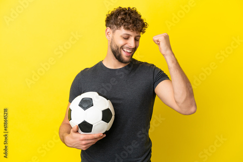 Handsome young football player man isolated on yellow background celebrating a victory