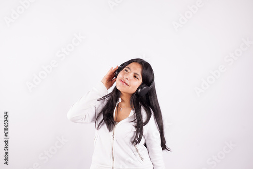 Photograph of young woman listening to music on a white studio background. Concept of music and hobbies.