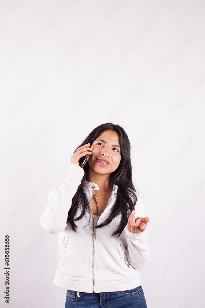 Photograph of young woman talking on the phone on a white studio background. Concept of people. Photograph of young woman talking on the phone on a white studio background. Concept of people.