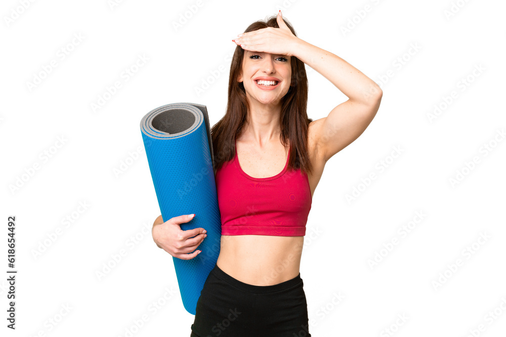 Young sport caucasian woman going to yoga classes while holding a mat over isolated chroma key background with surprise expression