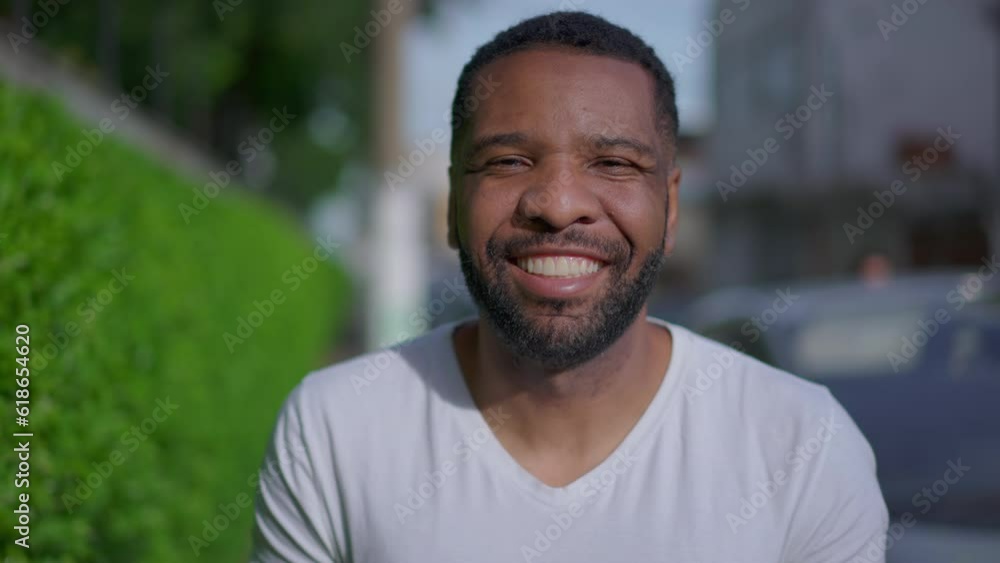One happy Brazilian black man walking forward in sidewalk toward camera, close-up face of African American person in tracking shot One happy Brazilian black man walking forward in sidewalk toward camera, close-up face of African American person in tracking shot
