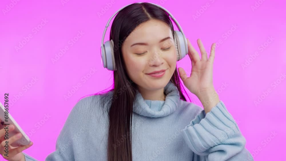Music, dance and phone with an asian woman in studio isolated on a pink background for streaming audio. Smile, freedom and headphones with a happy young female person listening to a radio playlist Music, dance and phone with an asian woman in studio isolated on a pink background for streaming audio. Smile, freedom and headphones with a happy young female person listening to a radio playlist