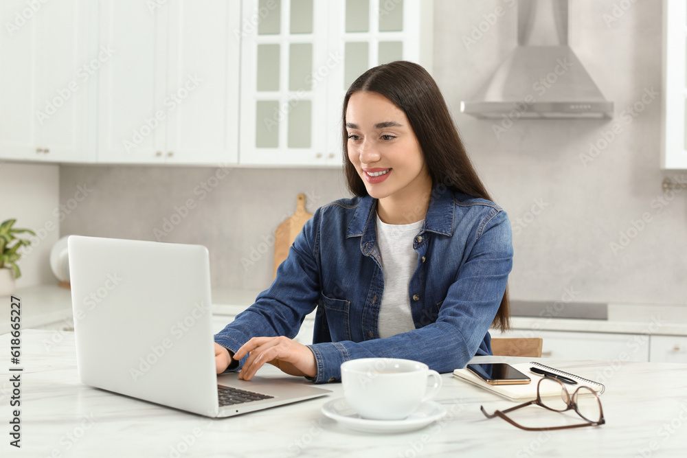Home workplace. Happy woman typing on laptop at marble desk in kitchen Home workplace. Happy woman typing on laptop at marble desk in kitchen