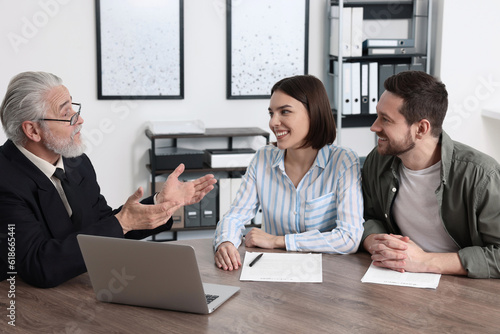 Obraz na plátně Young couple consulting insurance agent about pension plan at wooden table indoo